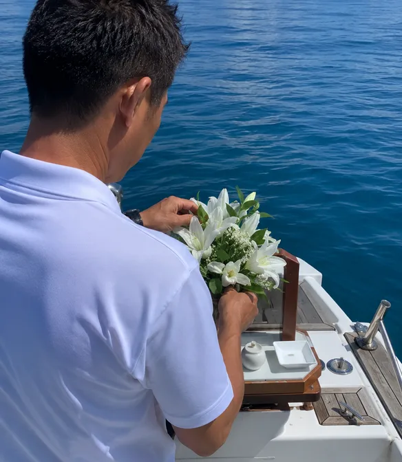 船上で花束を手に海を見つめる船長